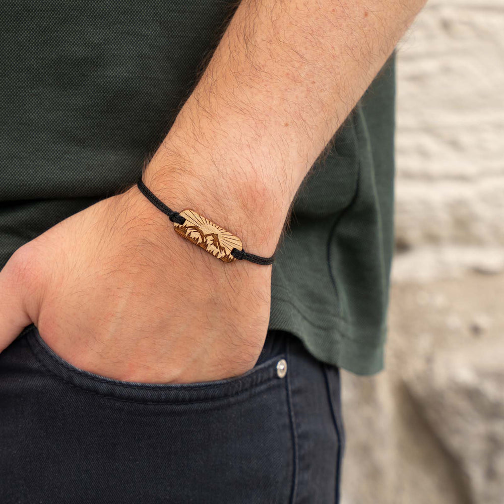 Armband mit Berg- und Waldmotiv auf Kirschholz – gravierter Holzschmuck mit Sonnenstrahlen und schwarzem Band