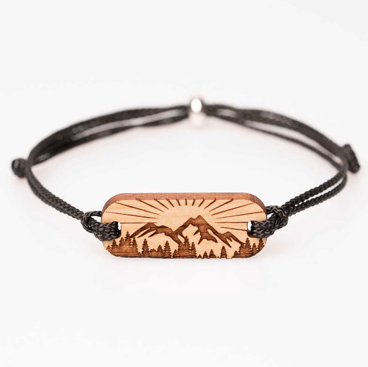 Handgefertigtes Kirschholz-Armband mit Berglandschaft, Sonnenstrahlen und Wald als Gravur, schwarzes Nylonband, individualisierbarer Holzschmuck – besondere Geschenkidee für Outdoor-Fans