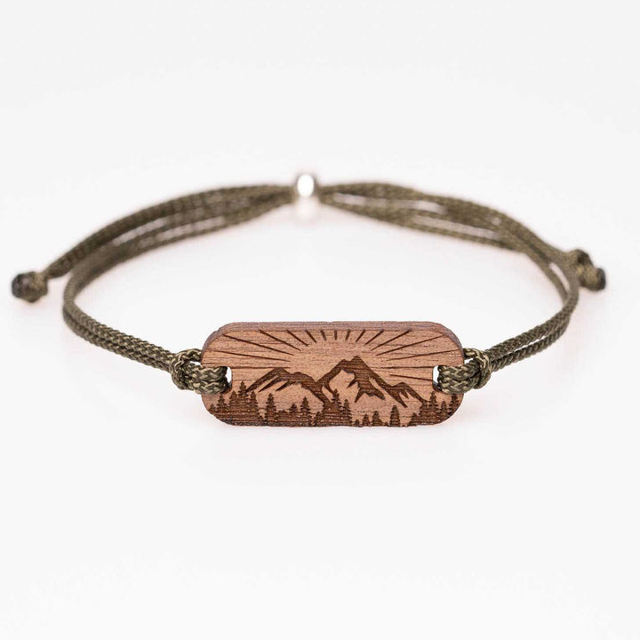 Handgemachtes Nussbaum Holzarmband mit gravierter Berg-Silhouette, Wald und Sonnenstrahlen, olivgrünes Nylonband, einzigartiger Outdoor-Schmuck – personalisiert als Geschenk für Naturfreunde