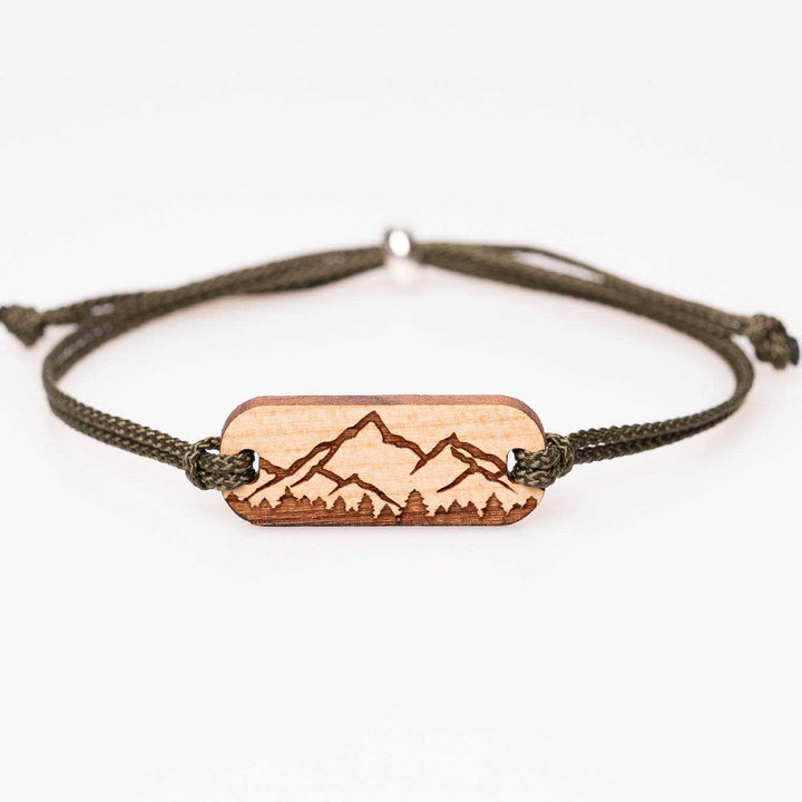 Personalisiertes Holzarmband aus Kirschholz mit Gravur: Berg Silhouette und Wald im Vordergrund, olivgrünes Nylonband, handgemachter Naturschmuck – perfektes Geschenk für Bergliebhaber und Naturfreunde