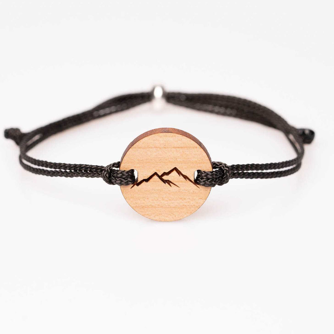 Personalisiertes Kirschholz-Armband rund mit Berg Silhouette Gravur, schwarzes Nylonband, handgemachter Holzschmuck – Geschenkidee für Naturfreunde und Outdoor-Fans.
