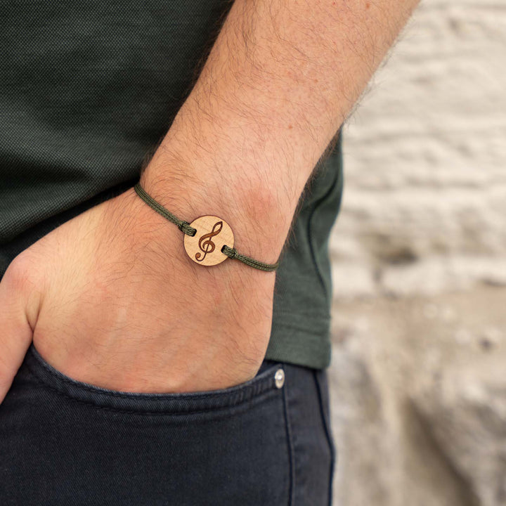 Armband mit Notenschlüssel-Gravur auf Kirschholz – musikalischer Holzschmuck mit olivgrünem Nylonband